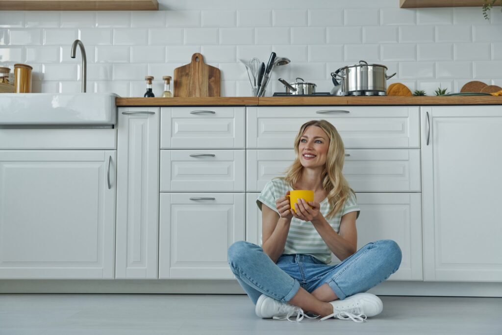 Woman Holding Cup While Sitting on The Kitchen Floor