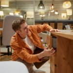 Young man freelancer choosing desk table for home office interior remodeling