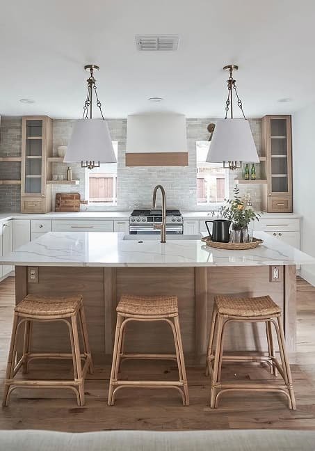 Modern transitional kitchen remodel featuring a white quartz waterfall island, rattan bar stools, pendant lights, and stone tile backsplash in Dallas.